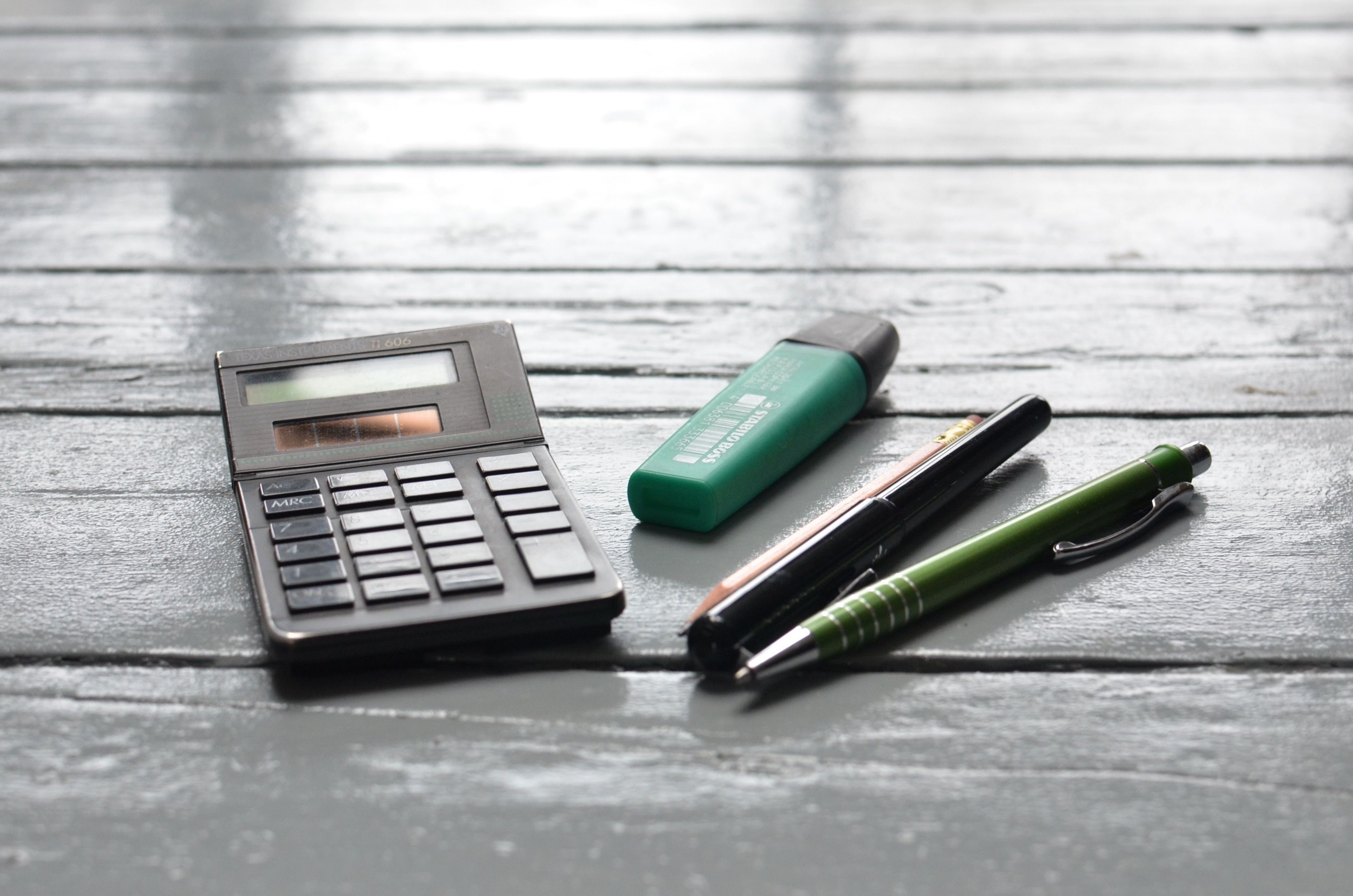 Calculadora y bolígrafos sobre una mesa de madera